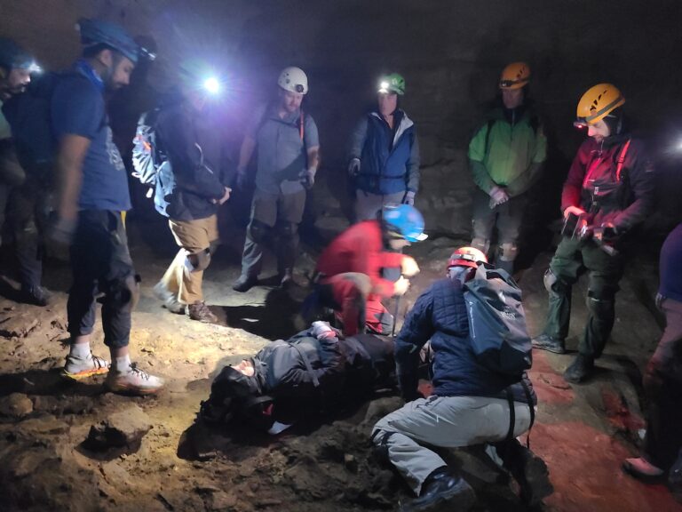 Executives work a simulated rescue by headlamp in the Cave Rescue Experience